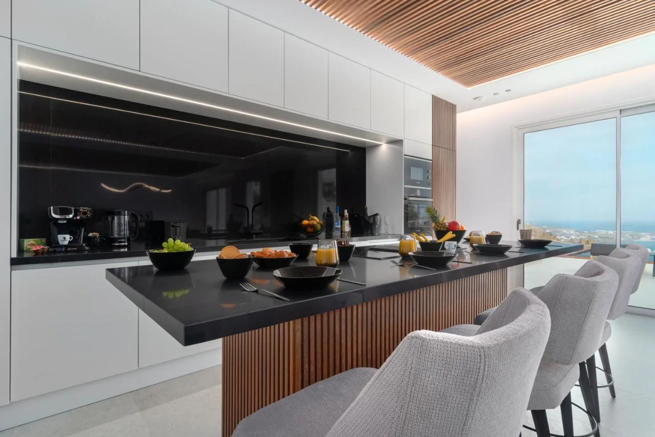 Modern kitchen with a dark island and seating beside a large window.