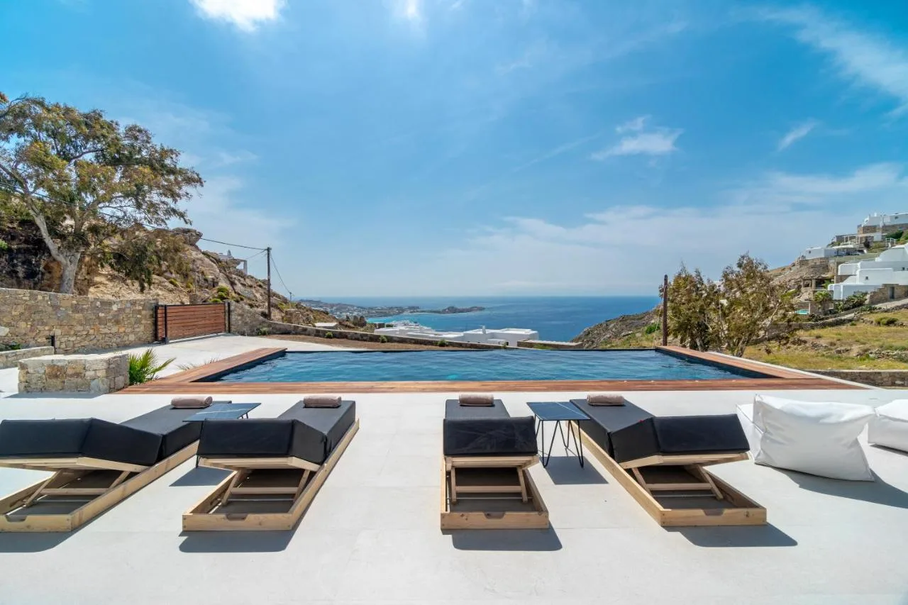 A seaside pool terrace with lounge seating and a view of the ocean.