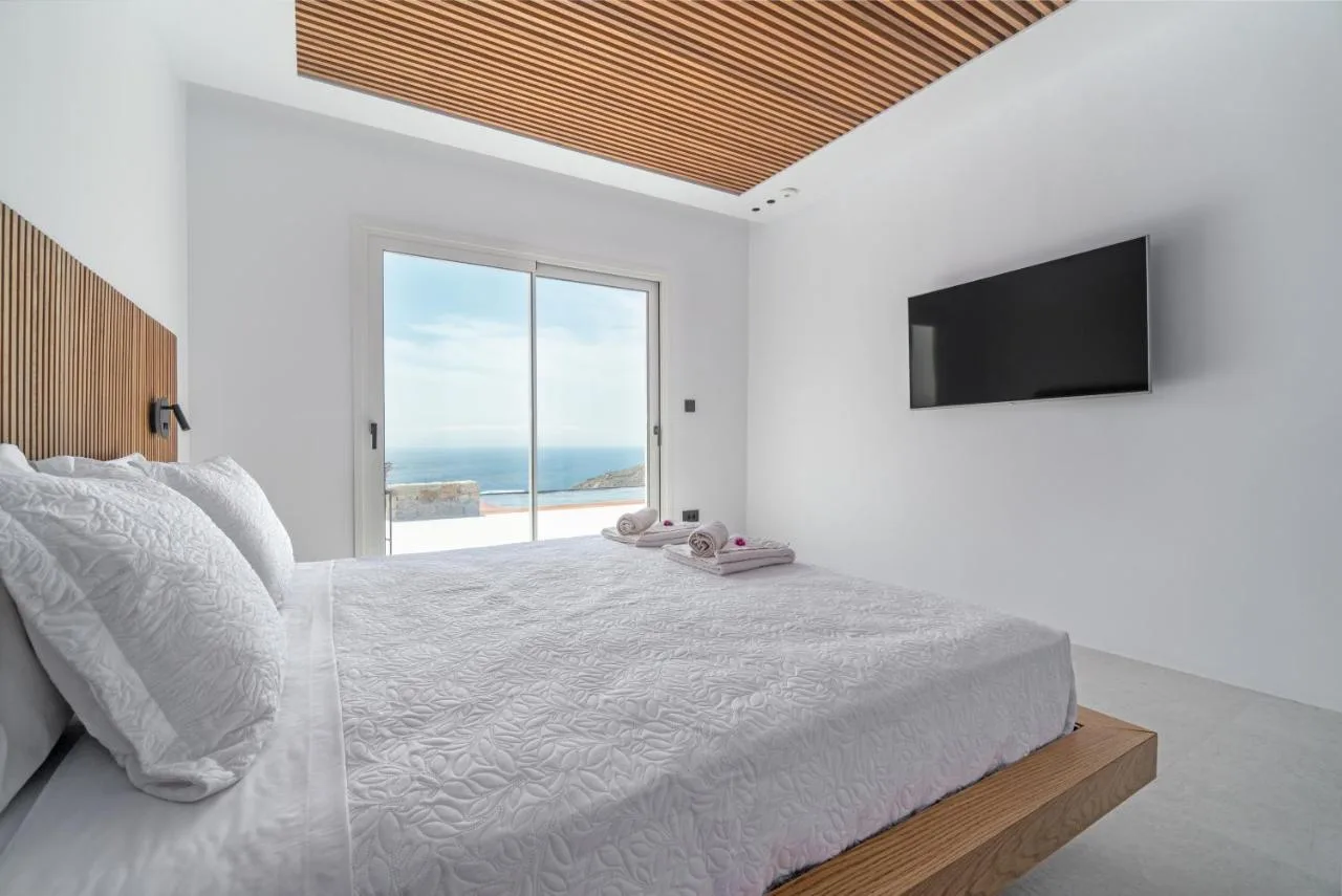 A bright bedroom with a large bed and sliding glass doors overlooking the sea.