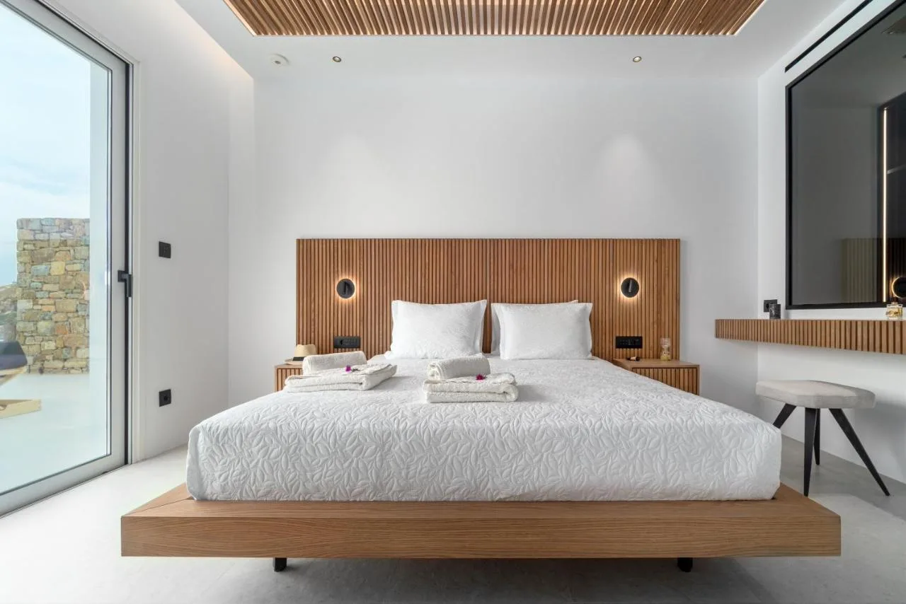 A bright bedroom with a large bed and a wood-paneled headboard.