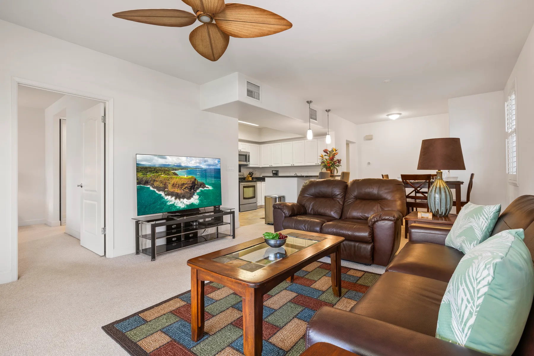 A bright living room with brown seating, a television, and a coffee table.