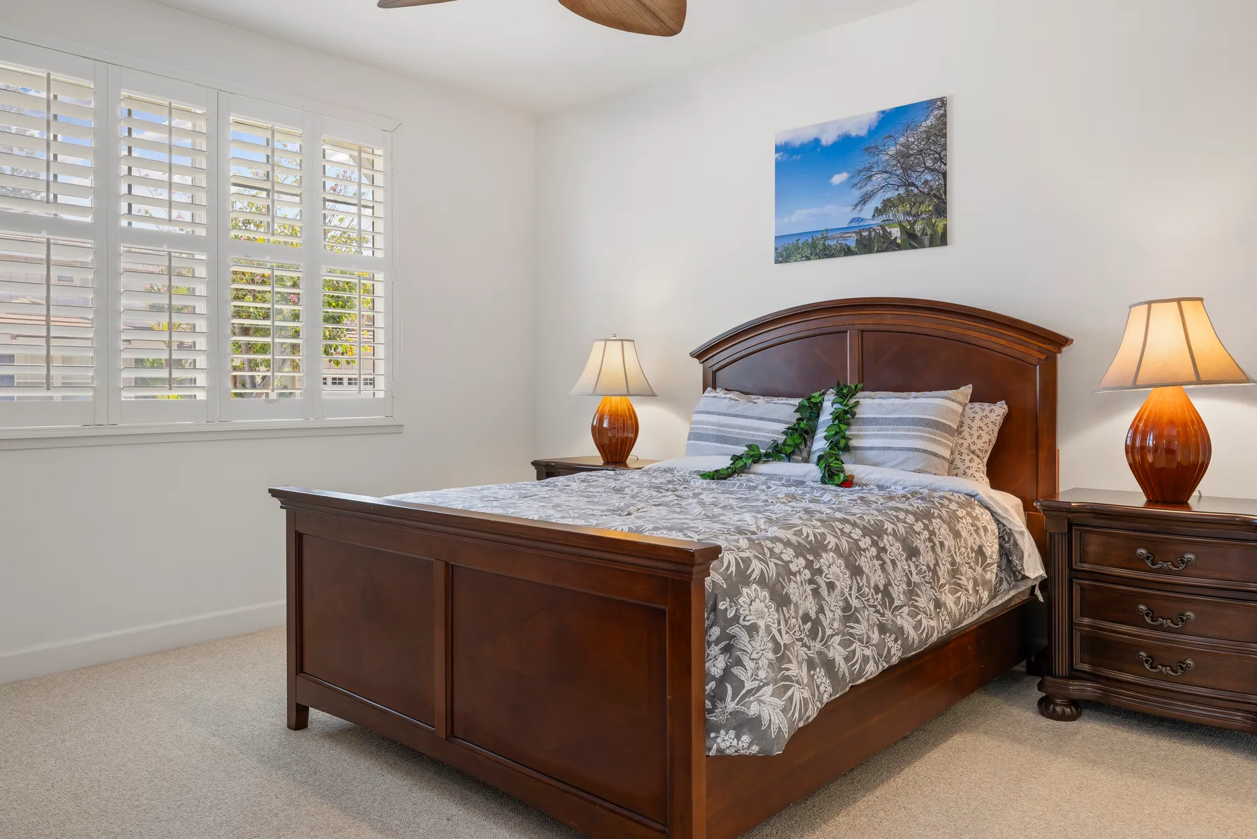 A bedroom with a wooden bed, patterned bedding, and matching bedside lamps.
