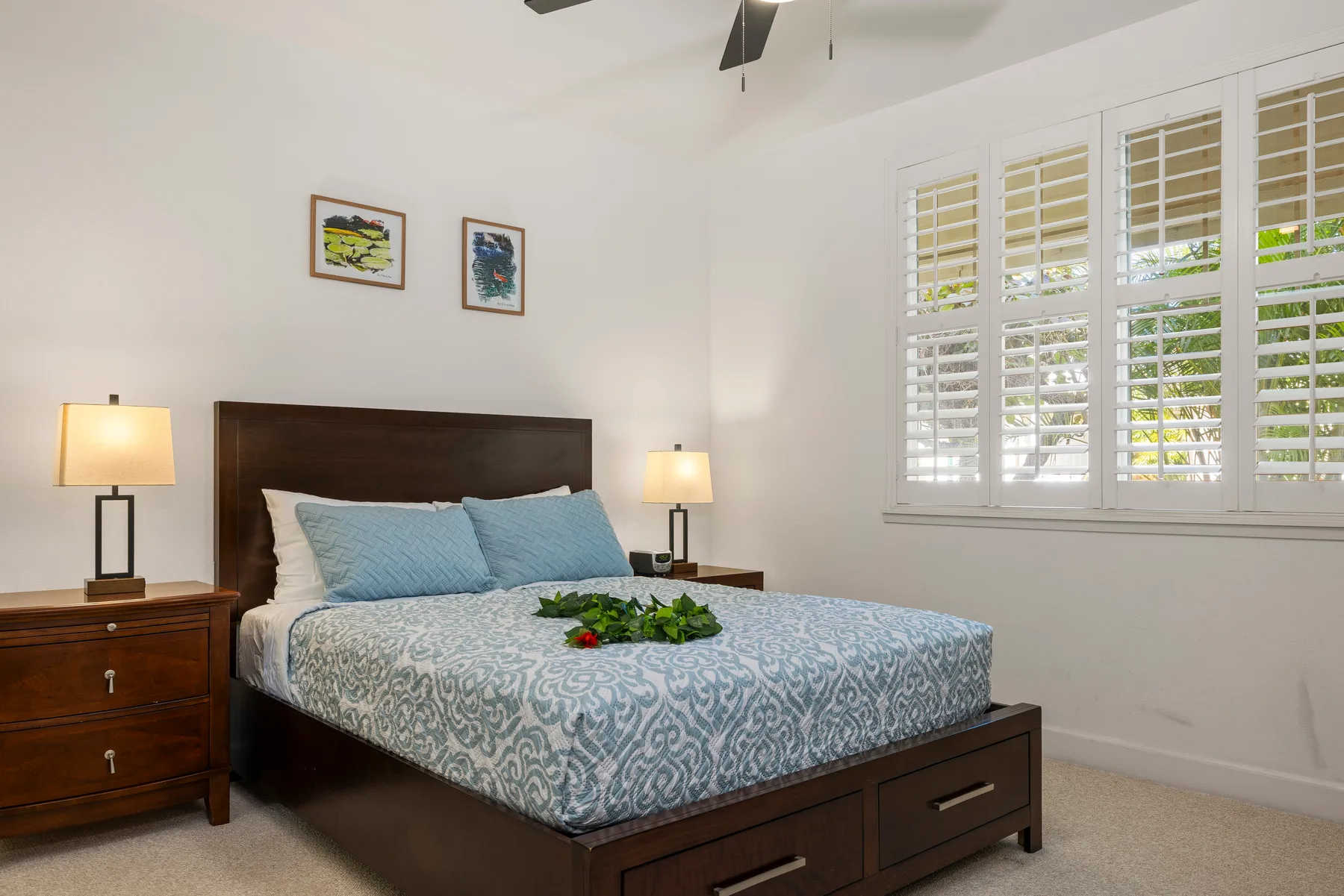 Un dormitorio con una cama, ropa de cama azul y ventanas con persianas.