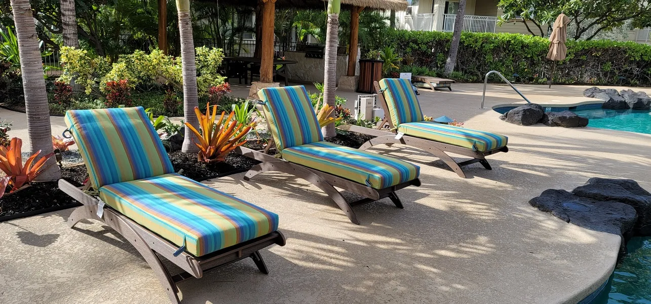 Zona de descanso junto a la piscina, con tumbonas a rayas y plantas tropicales.