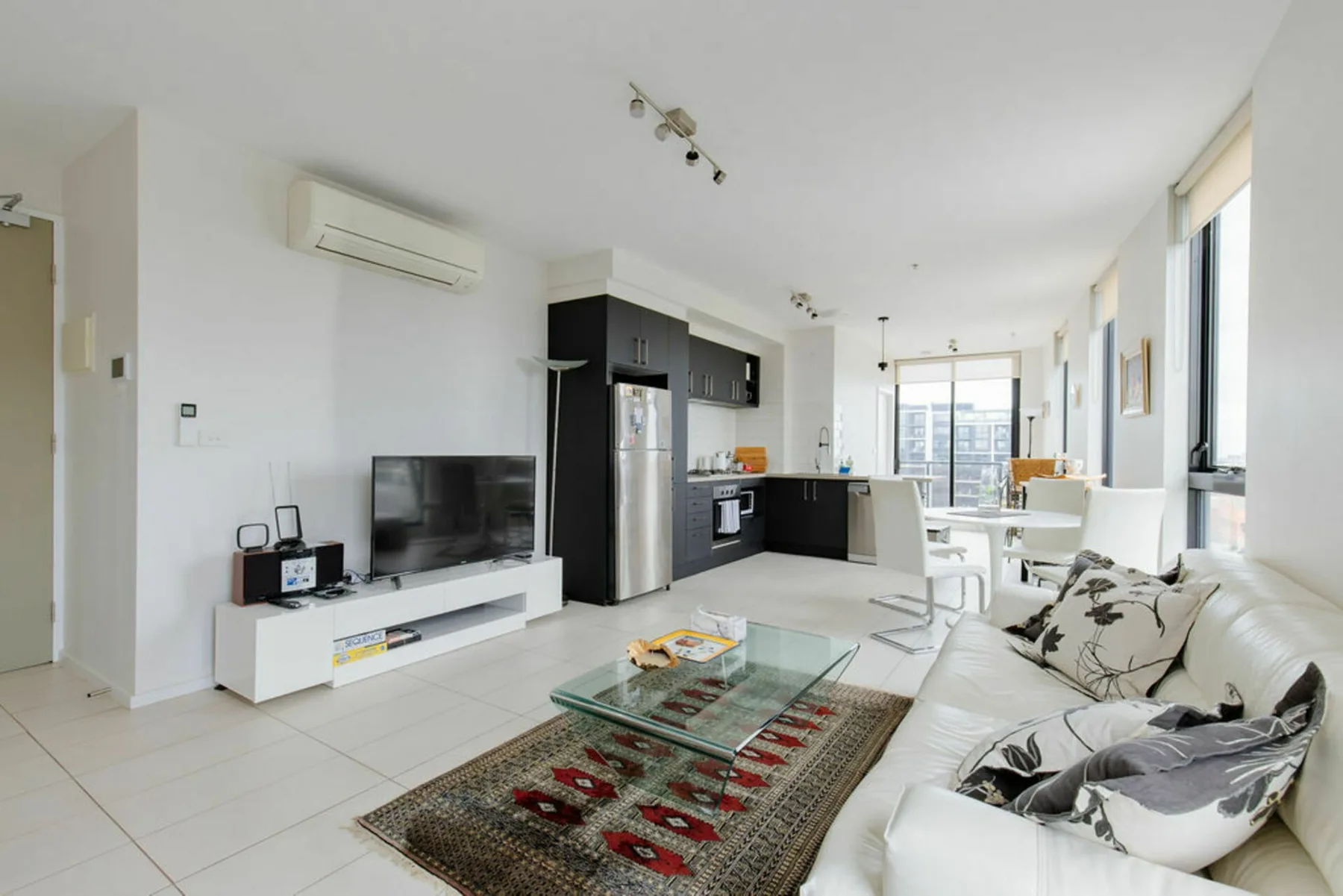 A bright living room opens onto a kitchen and dining area.