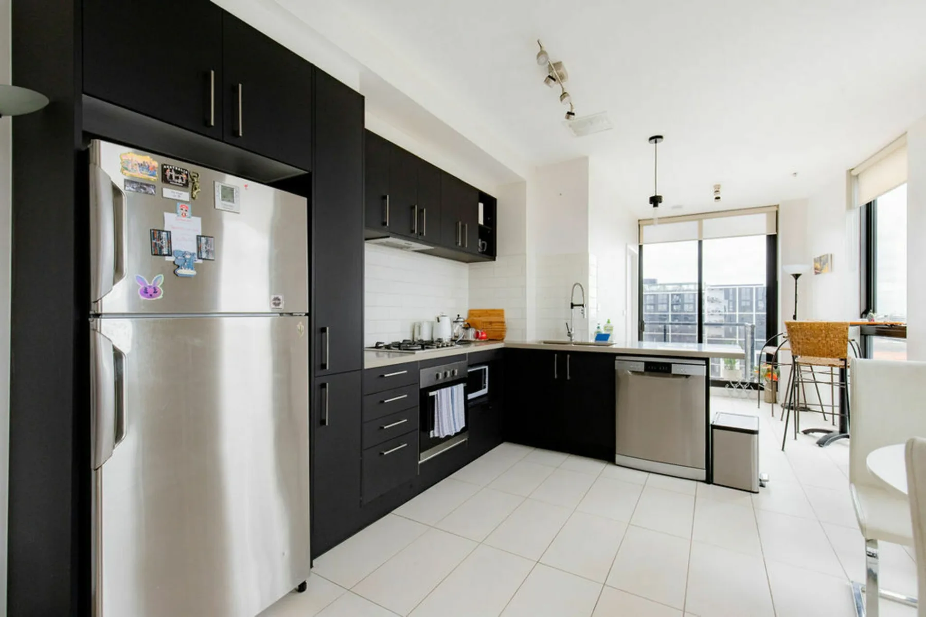 A modern kitchen with dark cabinets and stainless-steel appliances.