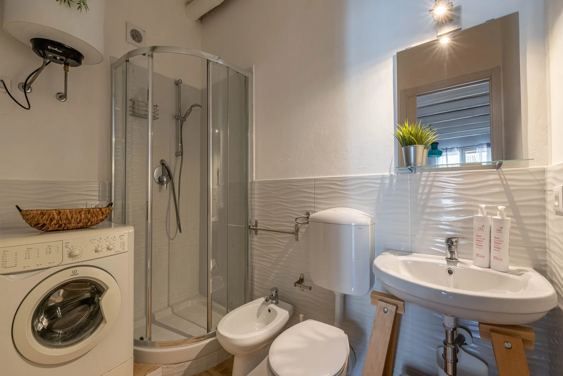 Un baño con ducha de vidrio, lavadora, inodoro y lavabo.