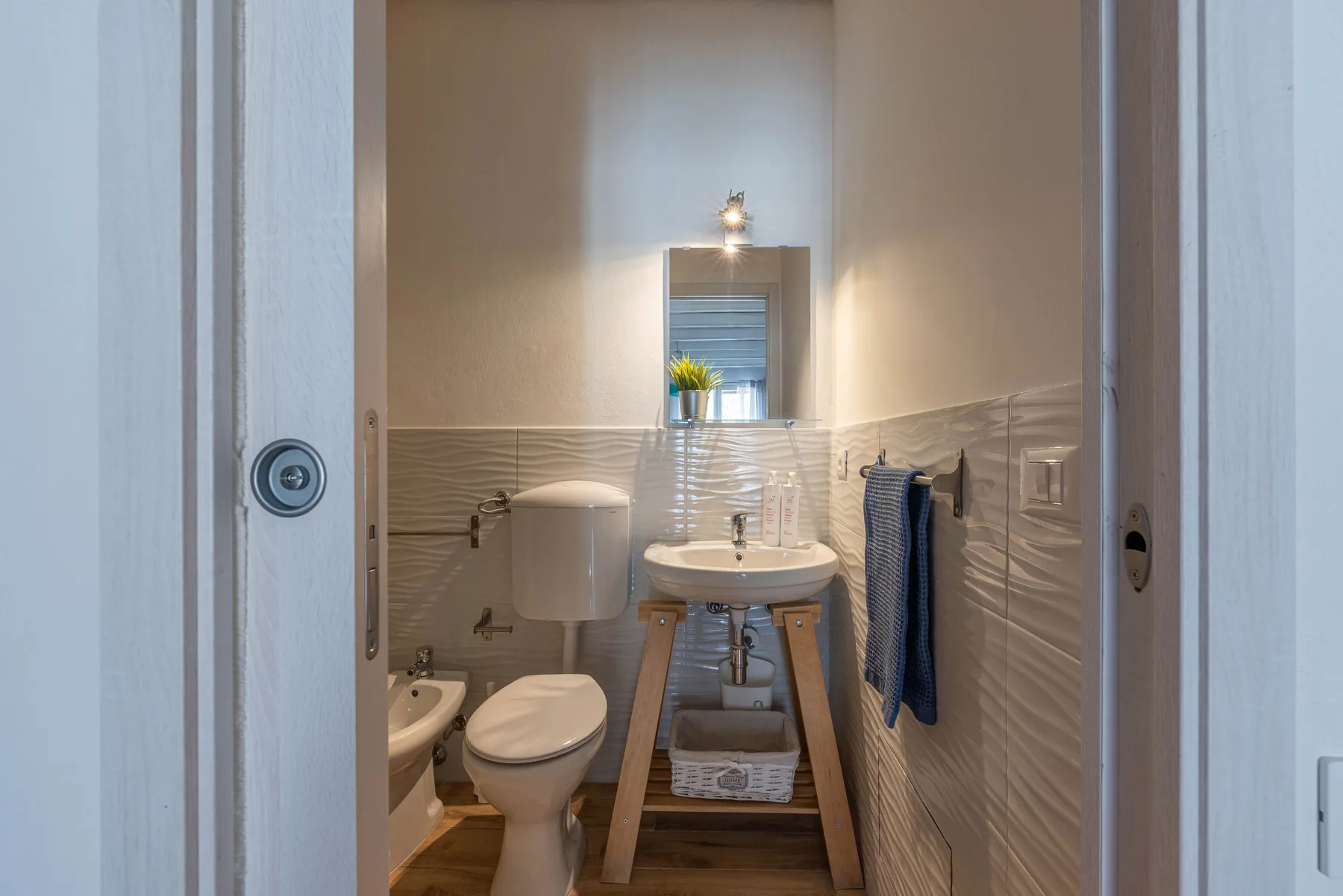 Un baño con lavabo, espejo, inodoro y toallas dobladas.