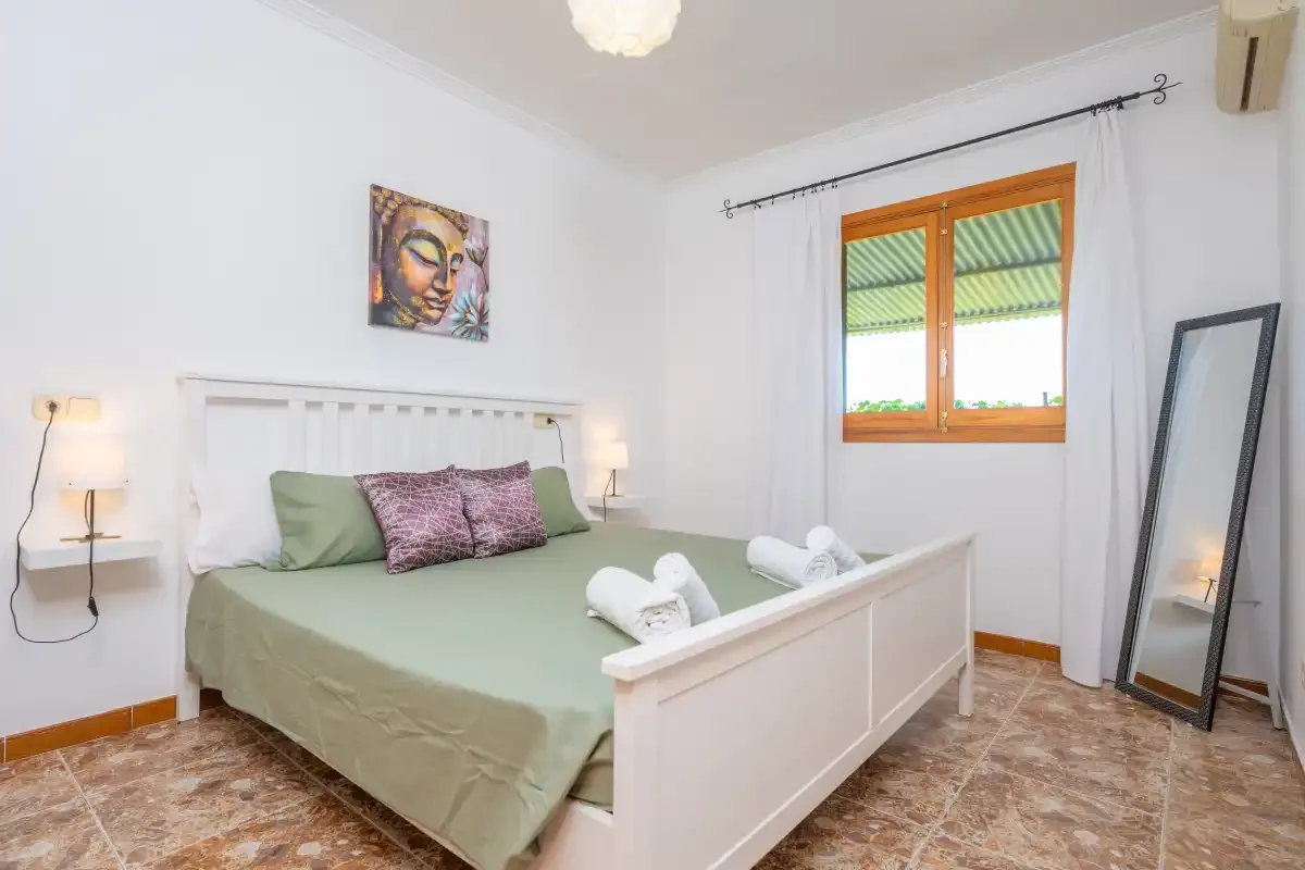 A bedroom with a bed, decorative pillows, and a window.