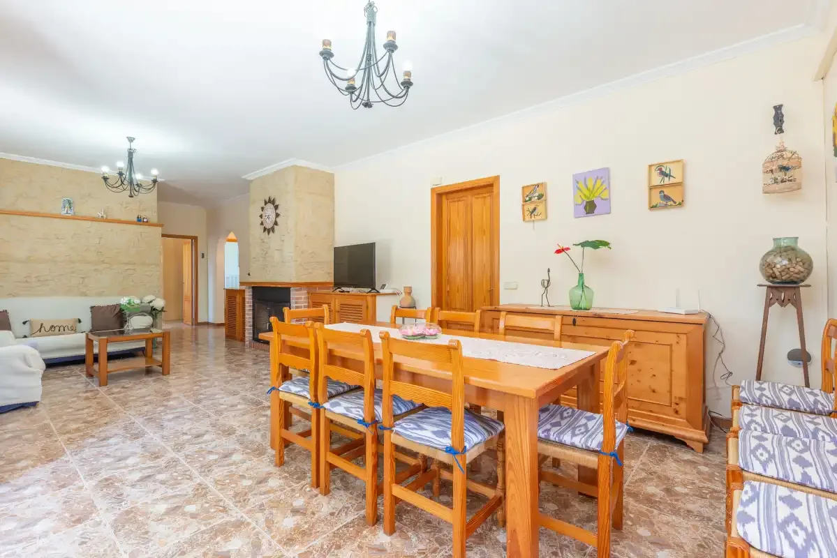 A dining area with a wooden table and chairs beside a living area.