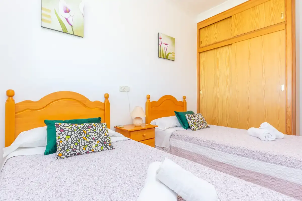 A bedroom with two beds and wooden headboards.