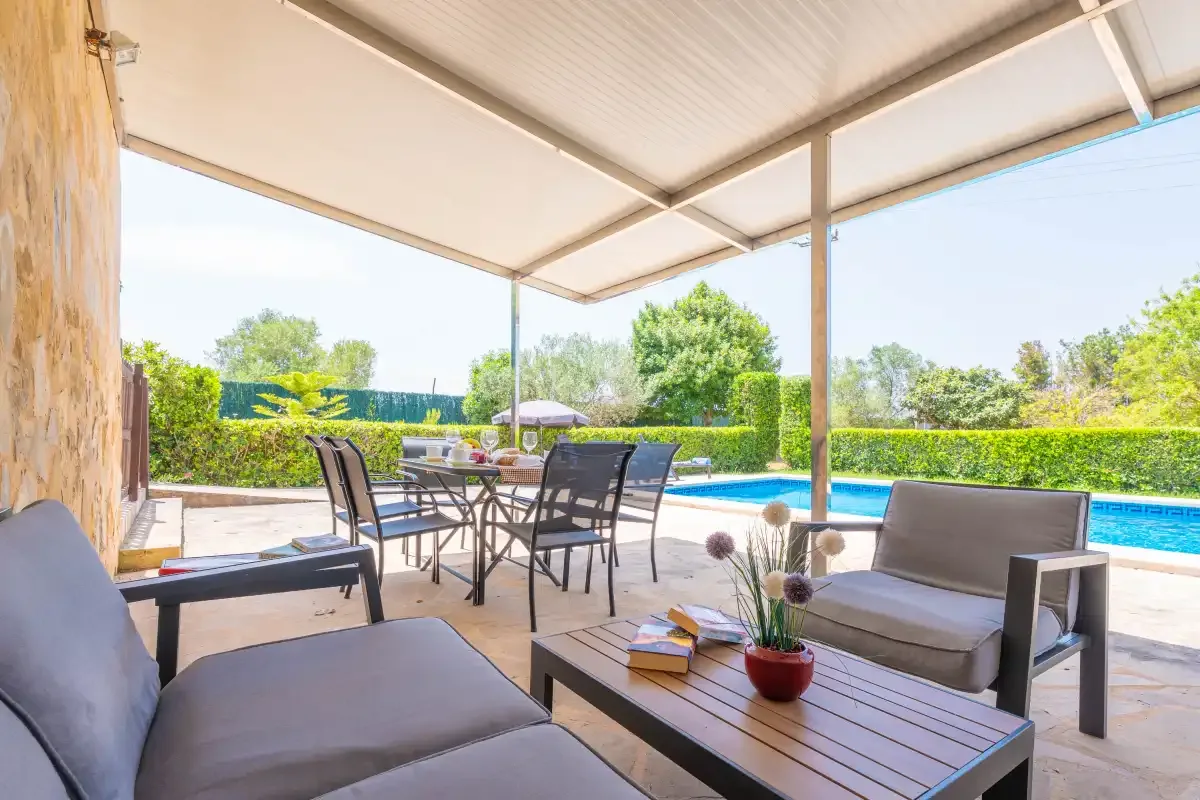 A covered outdoor seating area overlooks a swimming pool and garden.