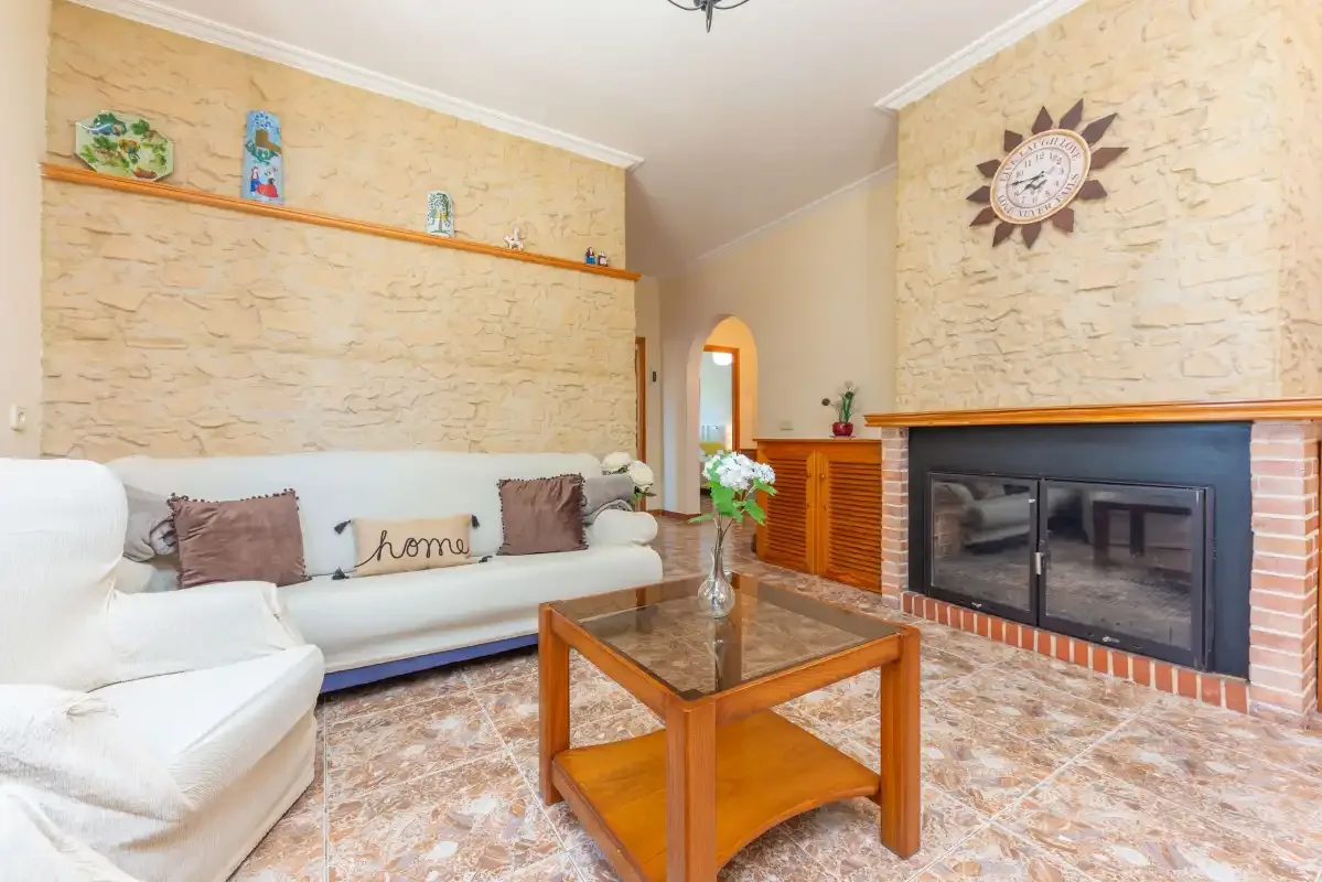 A living room with white seating, a wooden coffee table, and a fireplace.