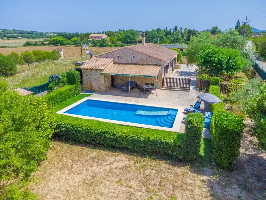 A countryside house with a swimming pool and surrounding greenery.