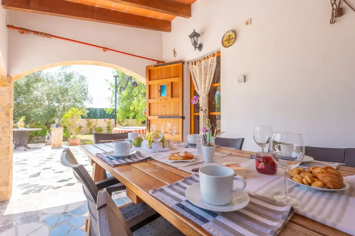 A dining area opens onto a bright patio with greenery.