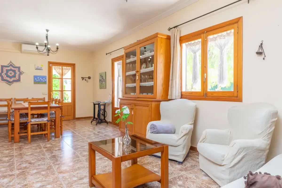 A living and dining room with wooden furniture and large windows.