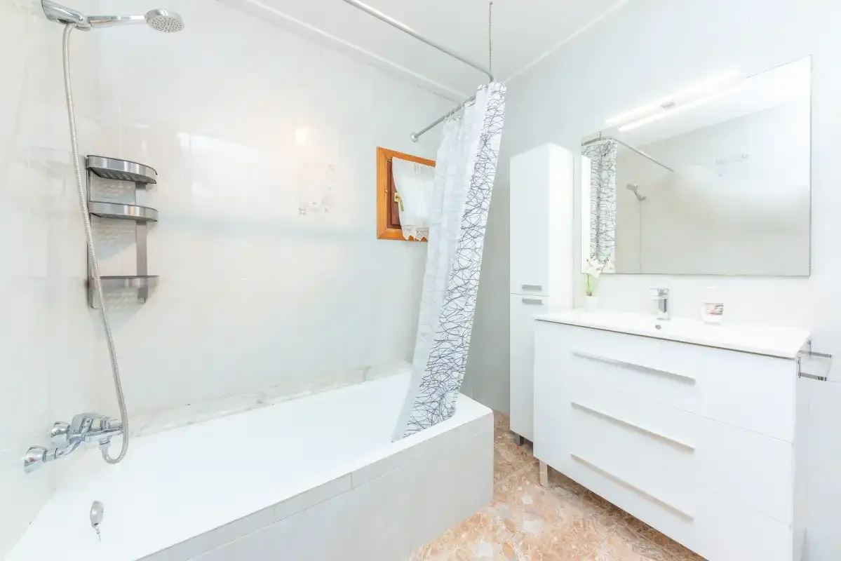 A bright bathroom with a bathtub, shower, and vanity.