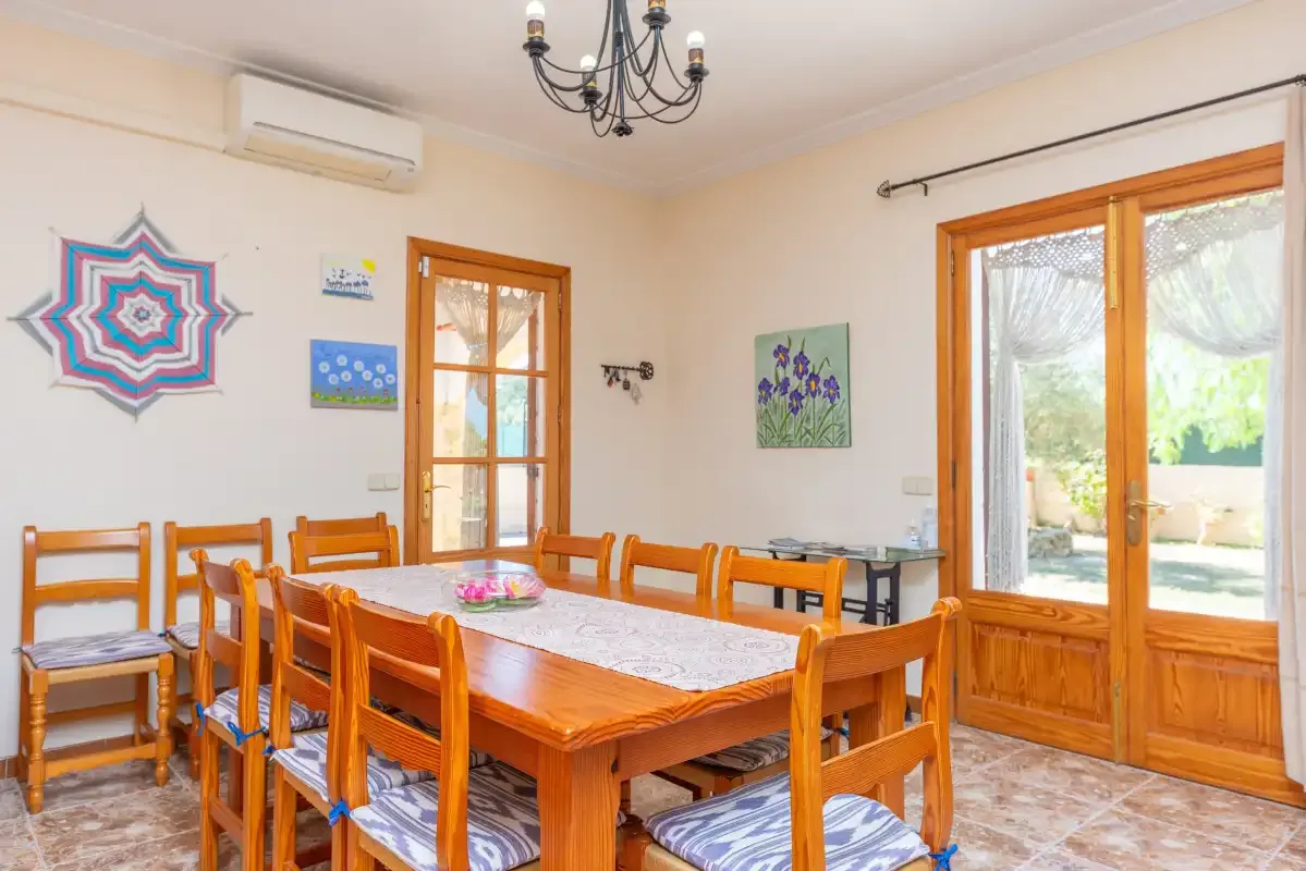 A dining room with a wooden table and chairs beside large glass doors.