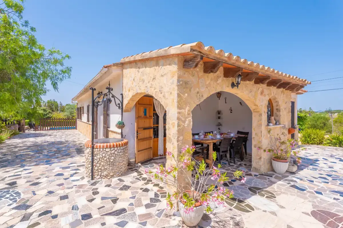 A stone house with an arched entrance and a covered outdoor dining area.