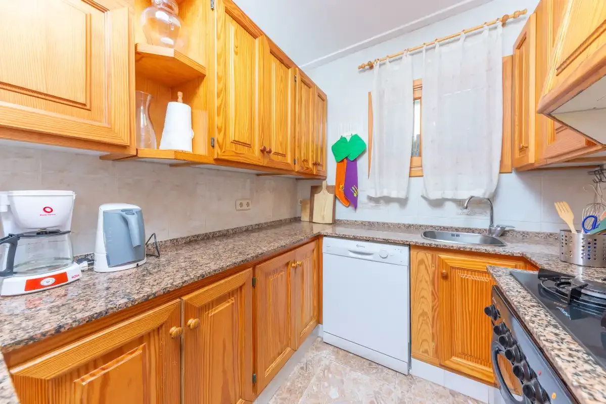 A kitchen with wooden cabinets, countertops, and a window above the sink.