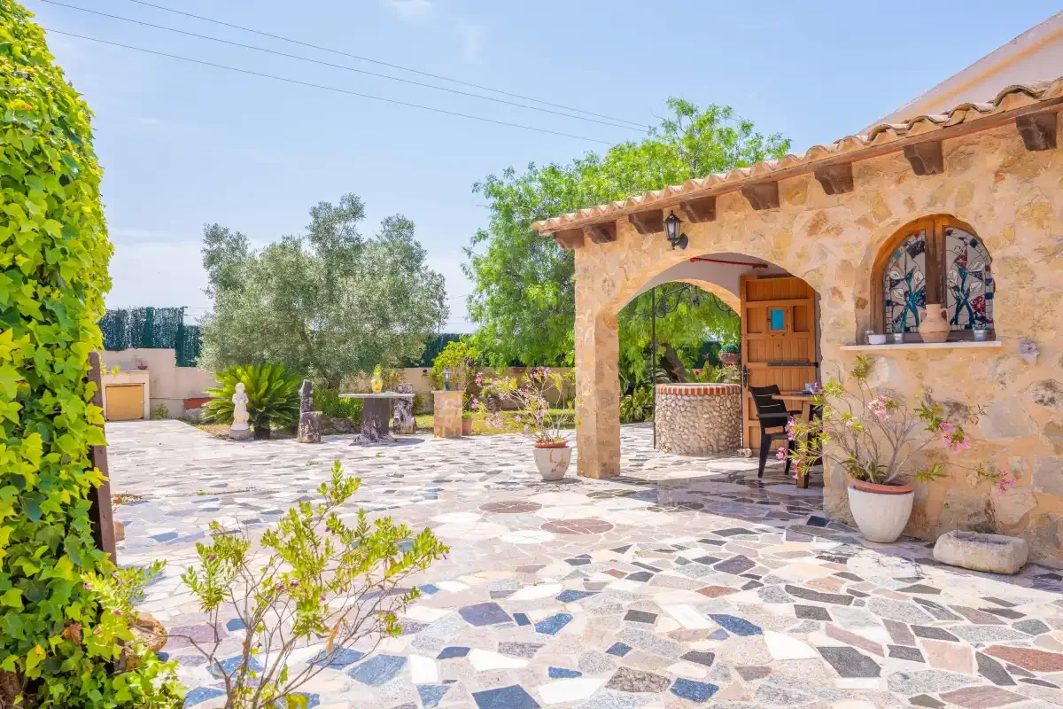 A stone patio with an arched entrance and potted plants.
