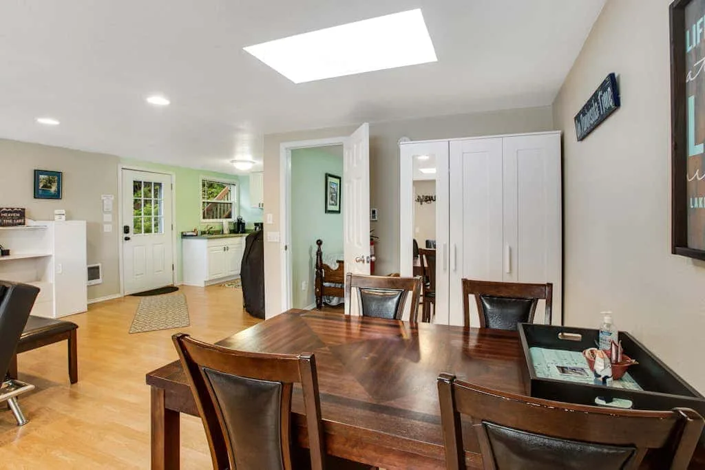 A dining area with a large wooden table and a kitchen visible beyond.