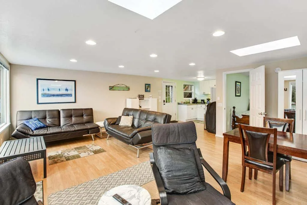 A bright open-plan living and dining area with seating and a wooden table.