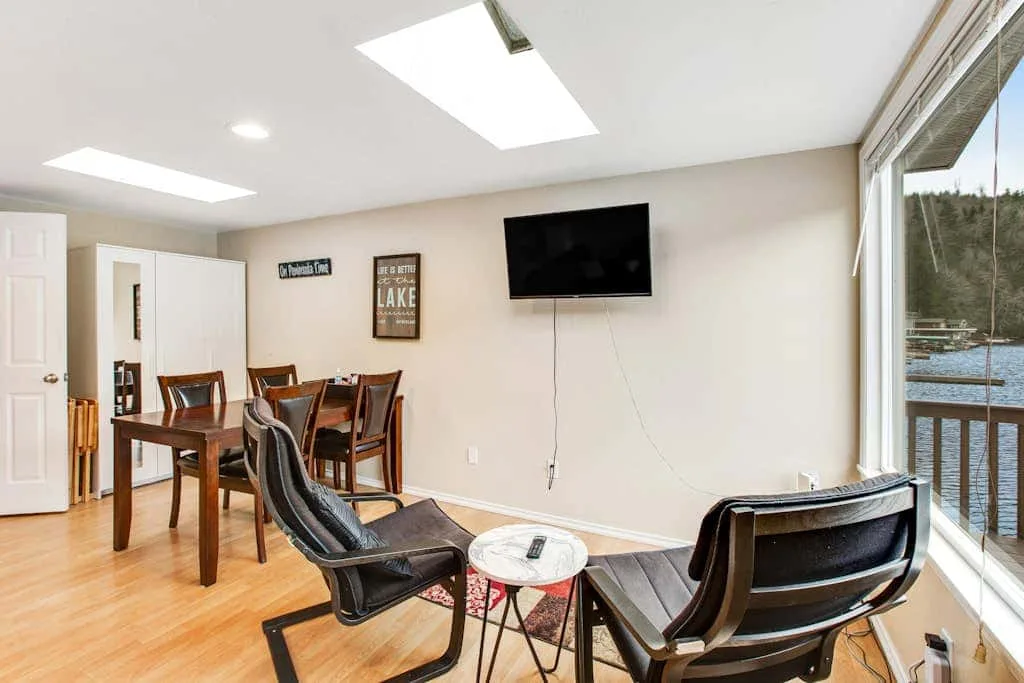 A dining and sitting area with a table, chairs, and a wall-mounted television.