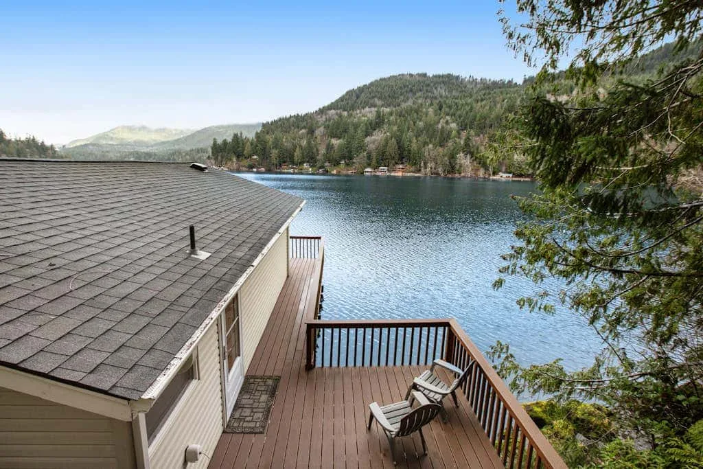 A wooden lakeside deck overlooks the water and forested hills.