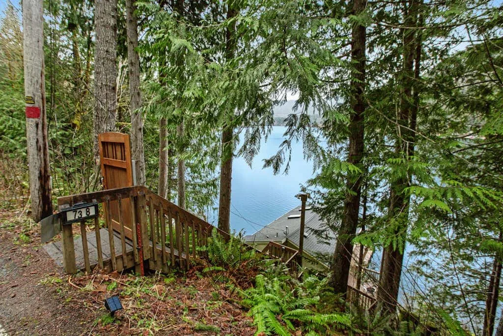 A wooded hillside path with wooden railings descends toward a view of the water.
