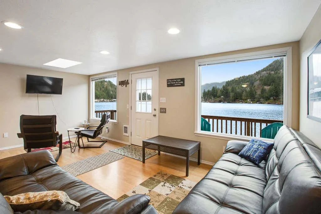 A living room with seating and a large window overlooking a lake.