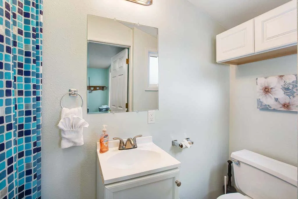 A bathroom vanity with a sink and mirror beside a blue tiled wall.