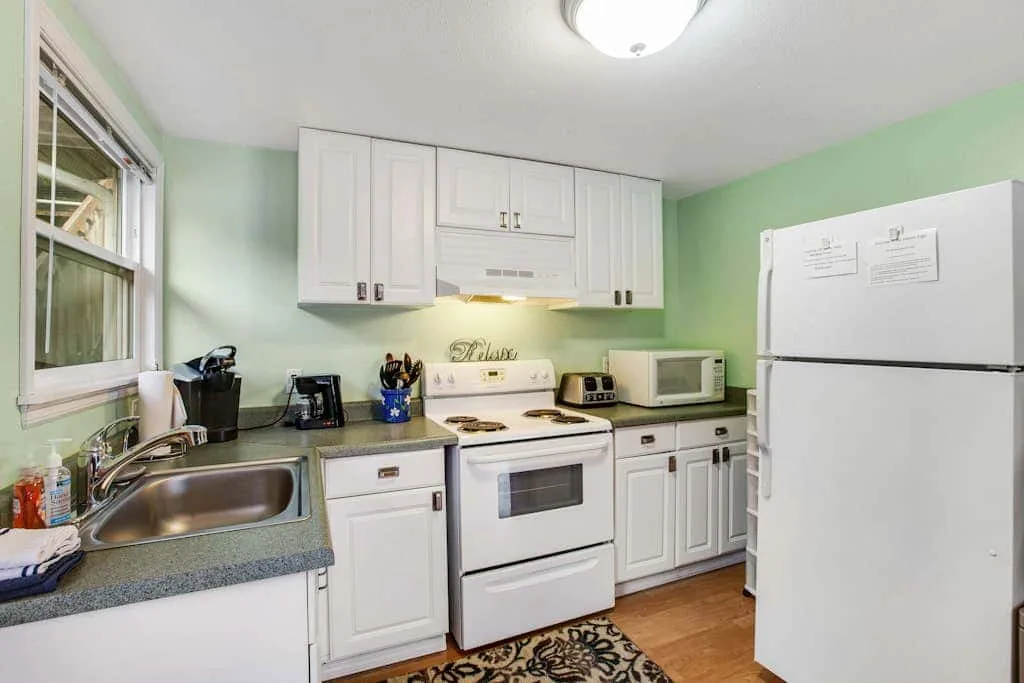 A kitchen with white cabinets, a stove, and a refrigerator.