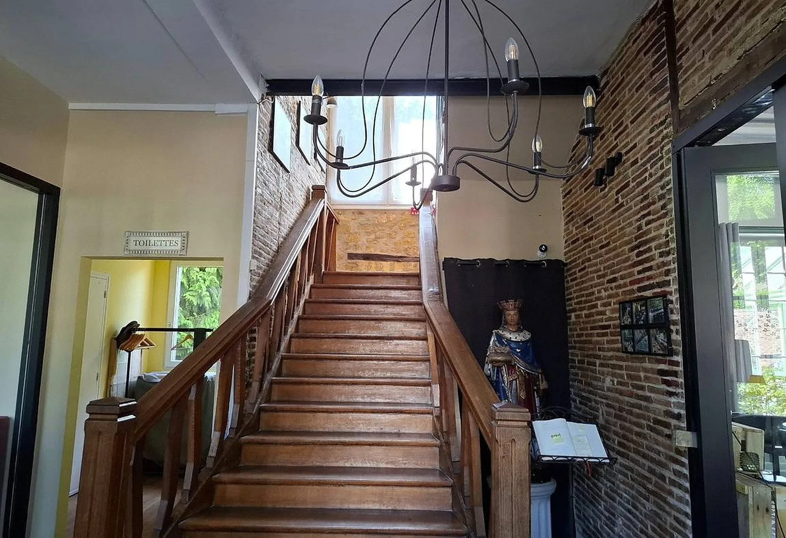 Escalera de madera y estatua de San Luis en el vestíbulo del hotel