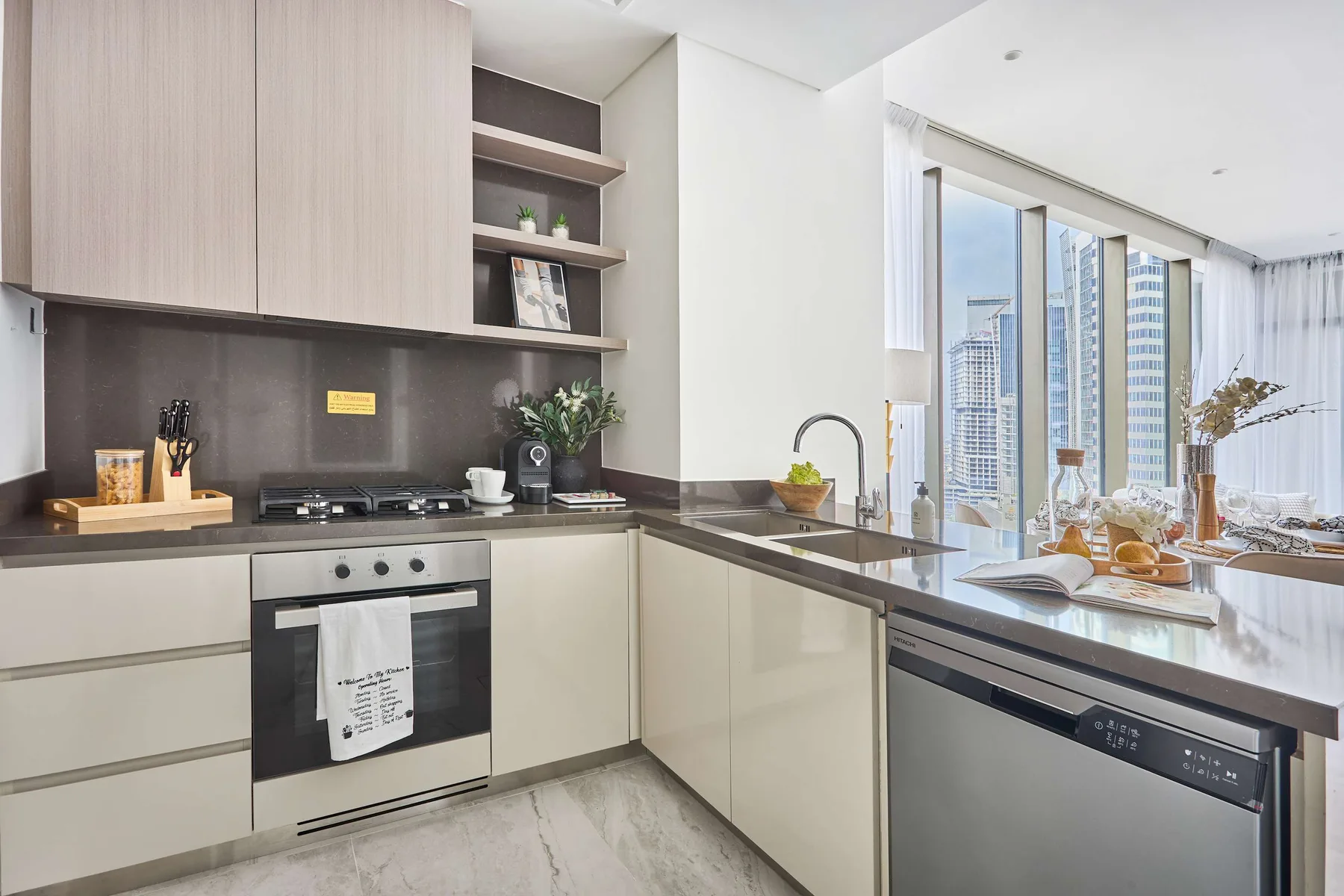 Una cocina moderna y luminosa con isla y grandes ventanas con vistas a edificios de la ciudad.