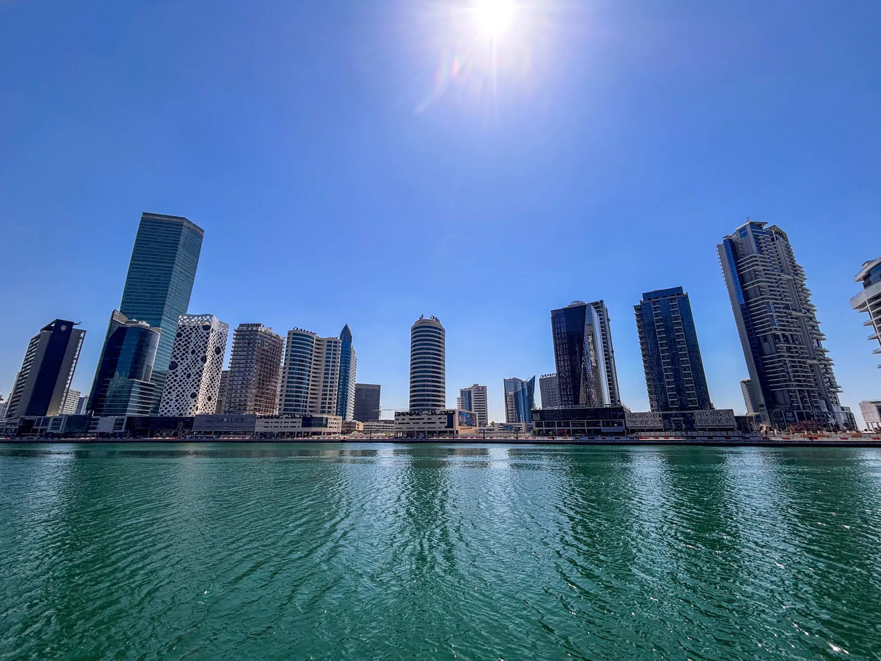 Un horizonte urbano de edificios altos se alza junto al agua bajo un cielo azul despejado.