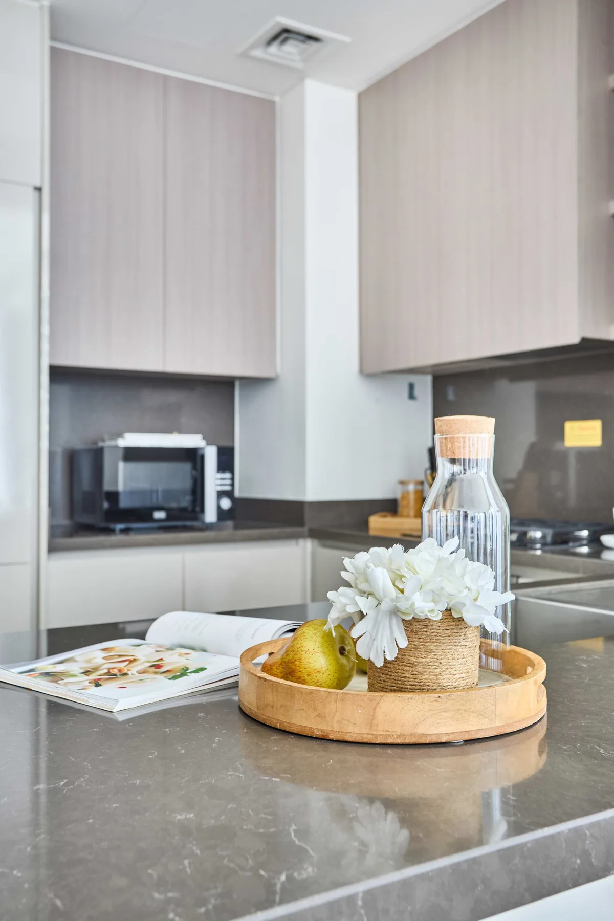 Una cocina moderna con una isla gris y una bandeja con fruta y flores.