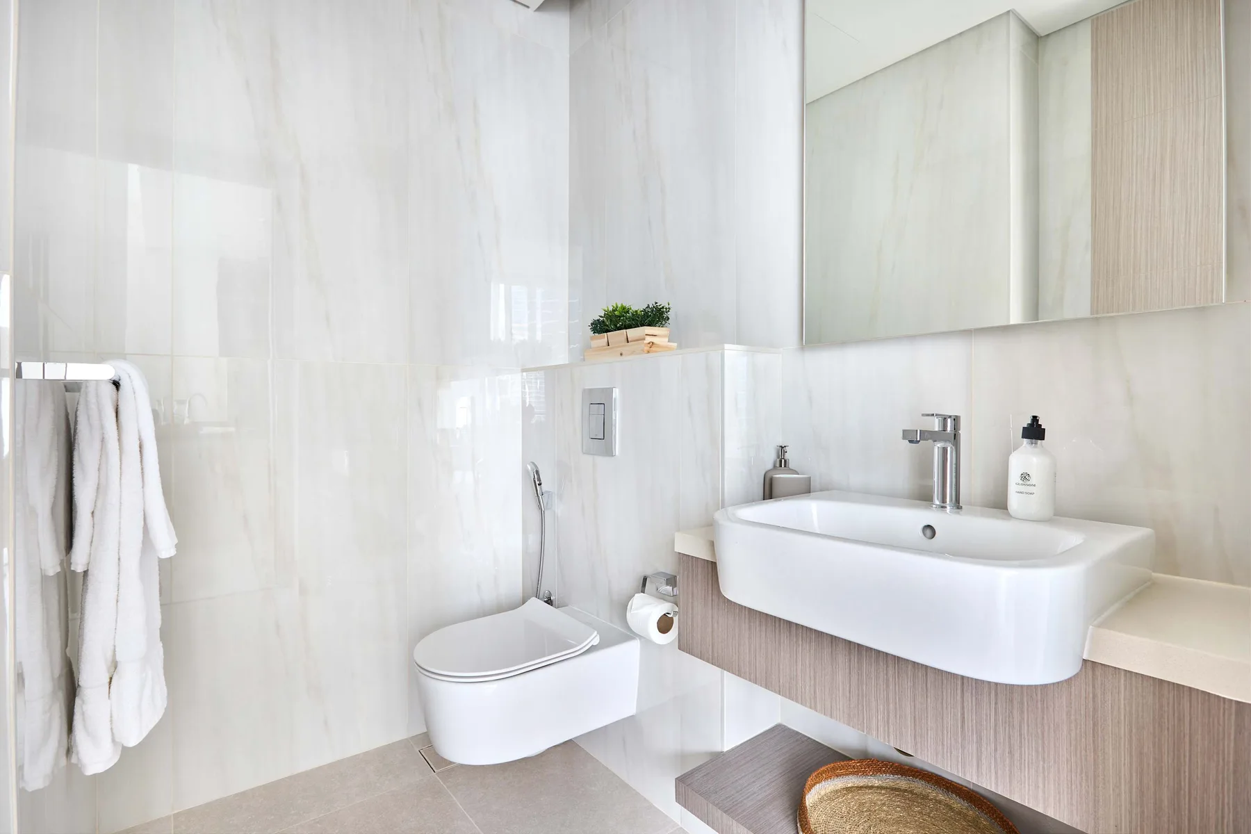 Un baño luminoso con lavabo suspendido e inodoro.