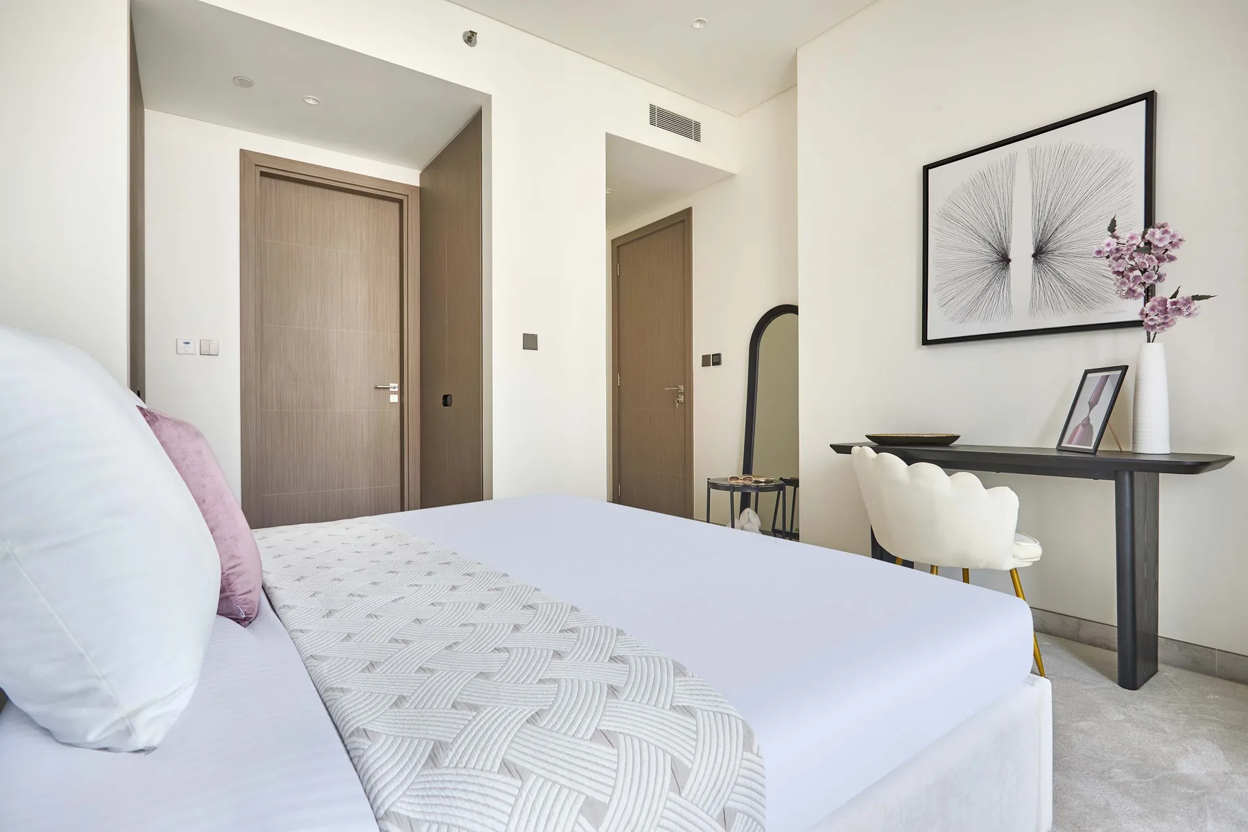 Un dormitorio luminoso con una cama, arte enmarcado y una mesa consola.