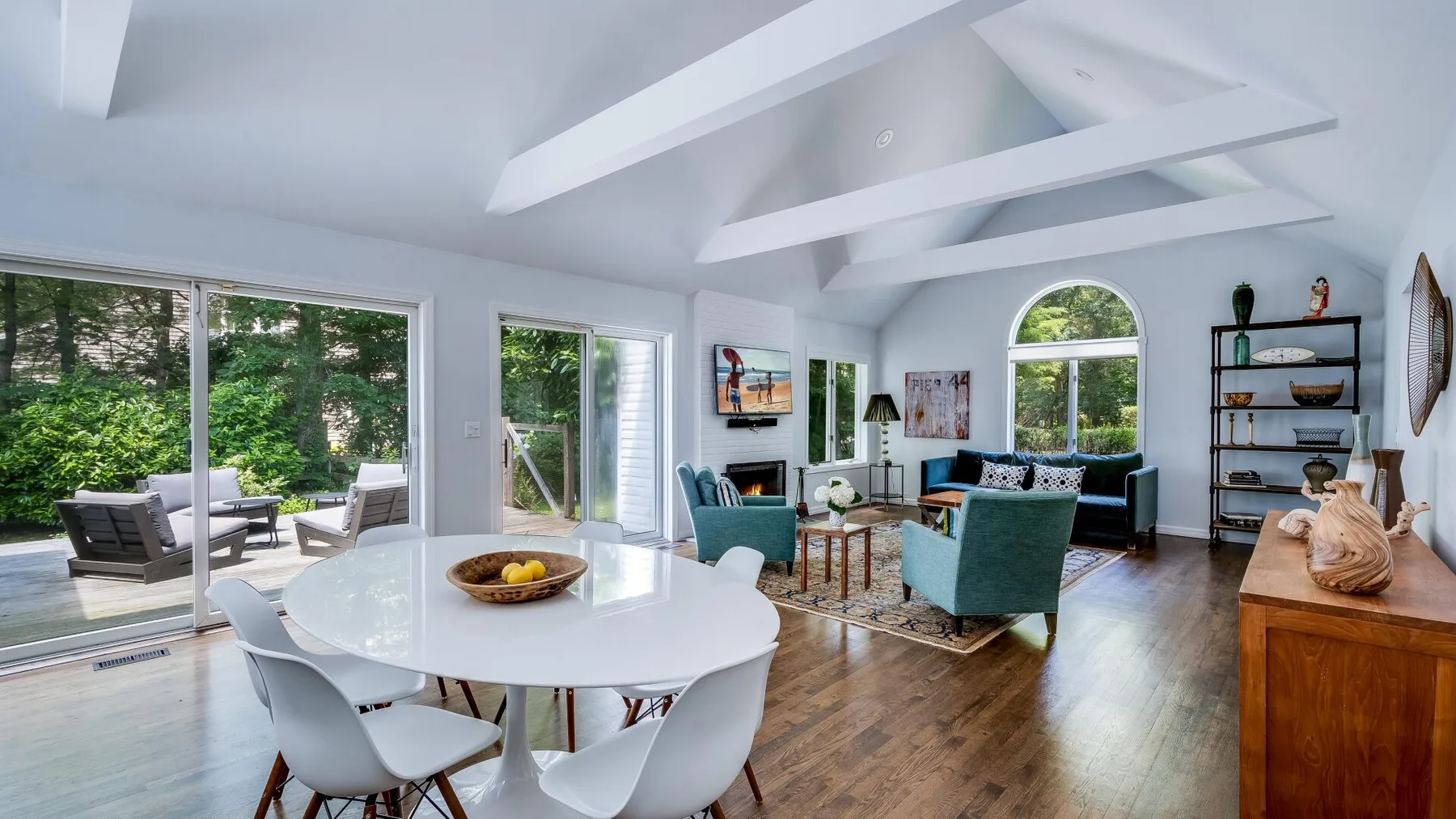 Una luminosa sala de estar y comedor con grandes ventanas y asientos alrededor de una mesa.