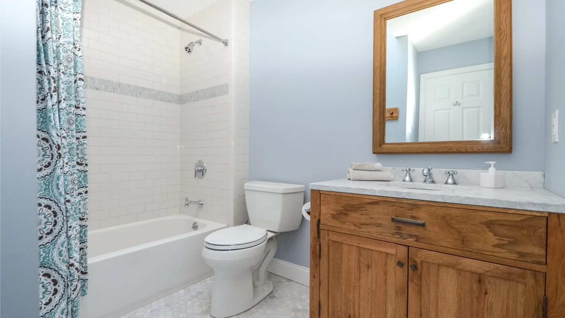 Un baño con bañera, inodoro y tocador de madera.