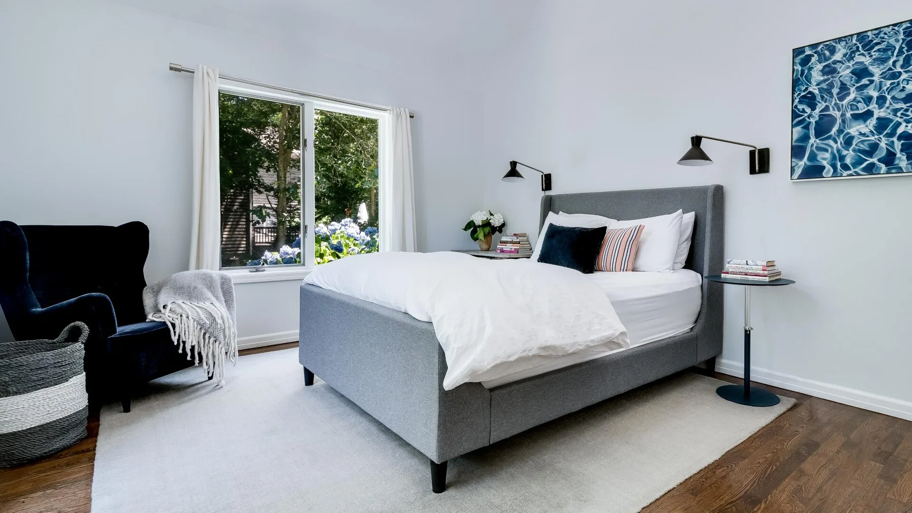 Un dormitorio luminoso con una cama tendida y una ventana amplia.