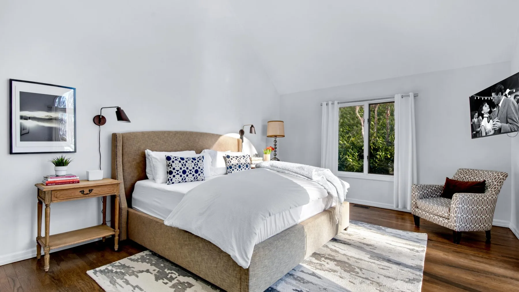 Un dormitorio luminoso con una cama grande y una ventana con vistas a la vegetación.
