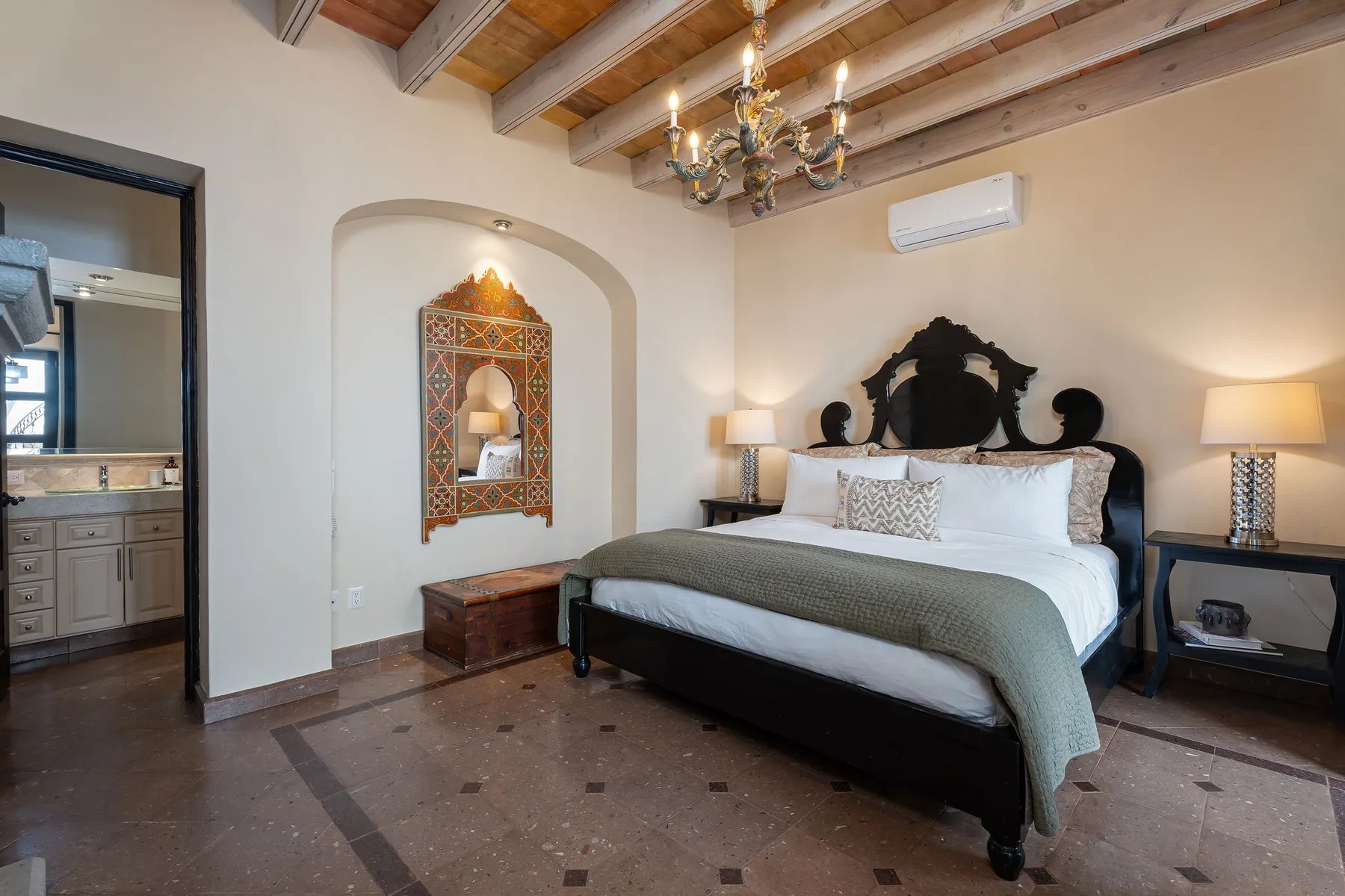 A bedroom with a large bed beneath exposed wooden ceiling beams.