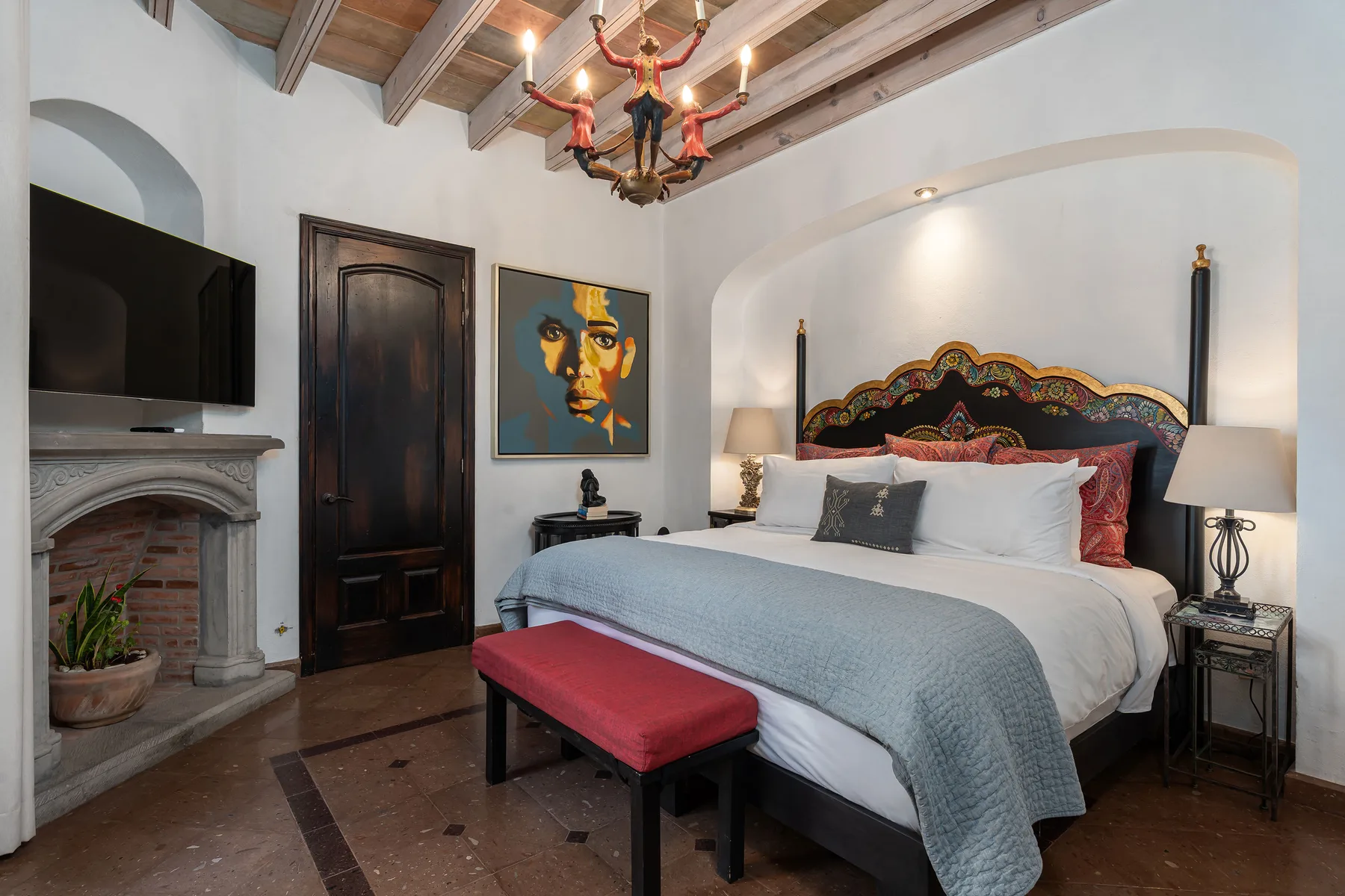 A bedroom with a large bed, a fireplace, and a television.