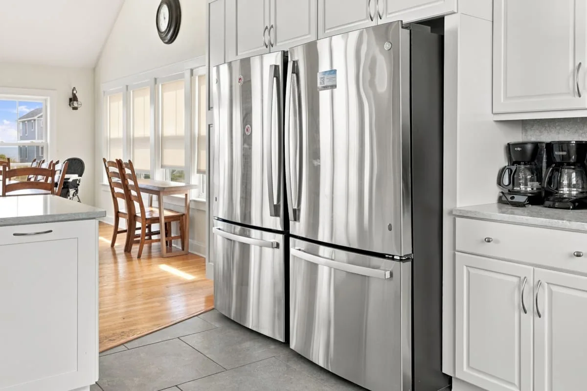 Una cocina luminosa con refrigeradores de acero inoxidable y gabinetes blancos.