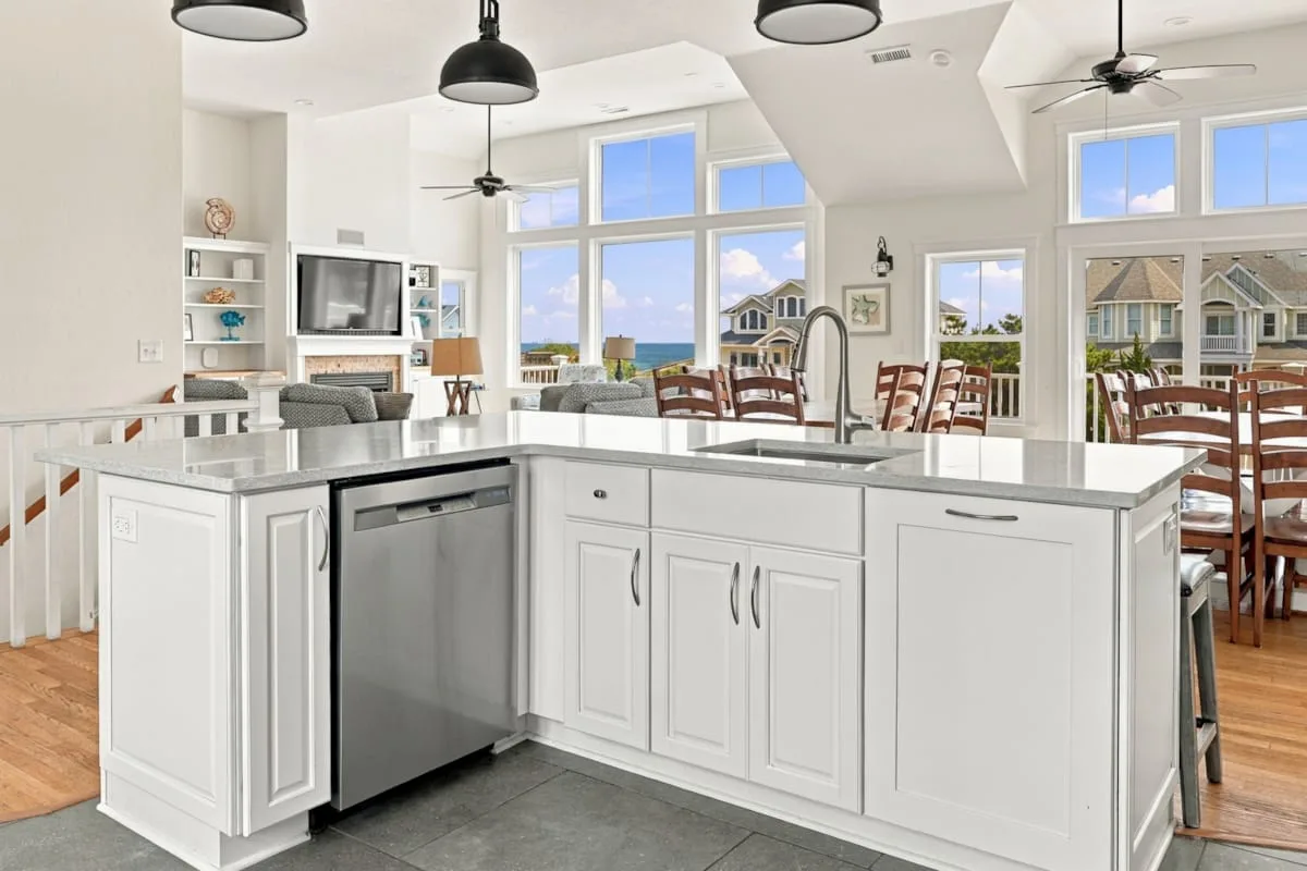 Una cocina luminosa con una gran isla blanca y ventanas con vistas al agua.