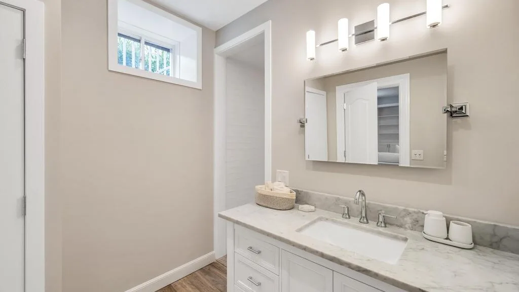 A bright bathroom features a vanity with a sink and a mirrored cabinet.
