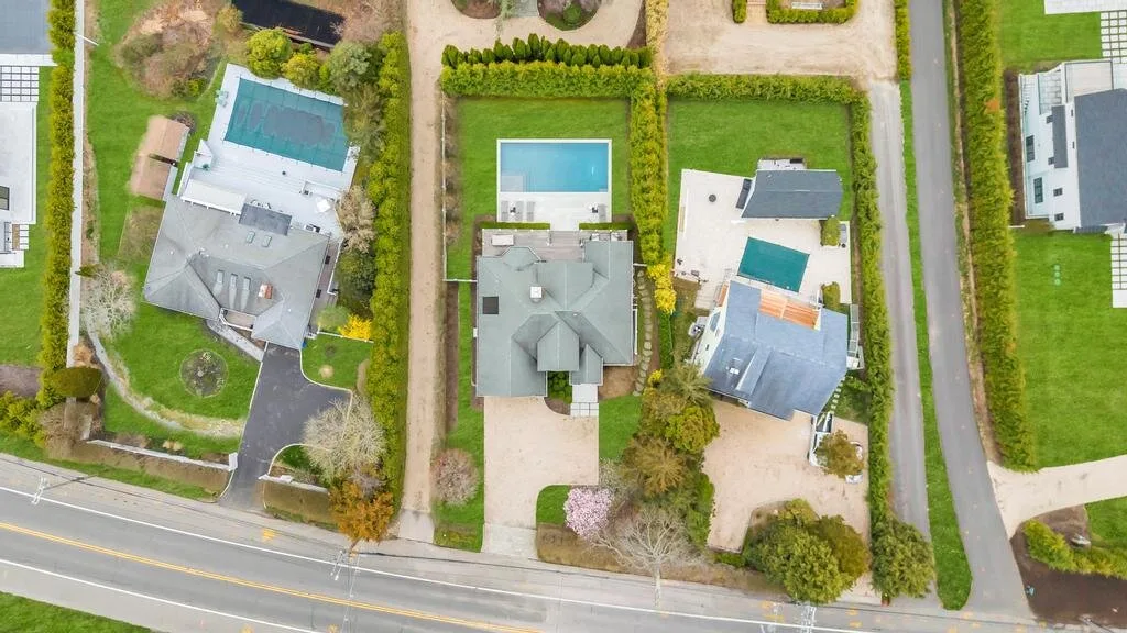 An aerial view of homes, gardens, and a road.