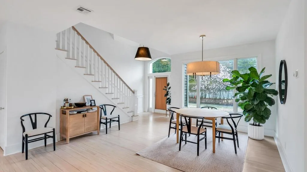 A bright dining area with a table, chairs, and large windows.